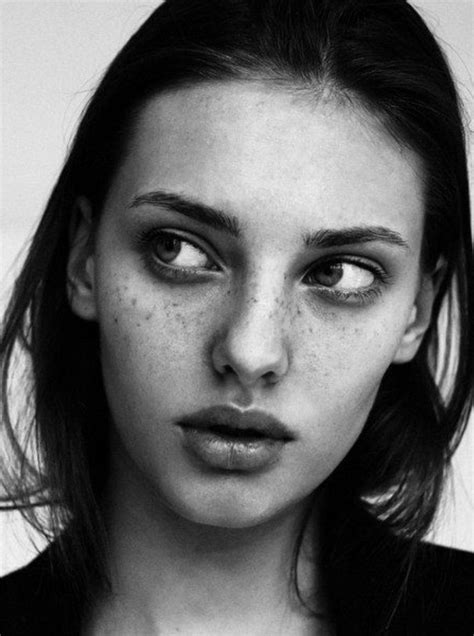 a black and white photo of a woman with freckles on her face looking at ...