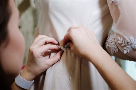 Premium Photo | Woman with dressmaker making final touch in bridal ...