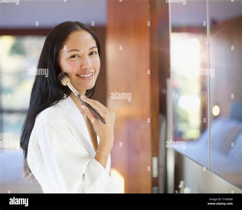 Portrait confident young woman applying makeup in bathroom mirror Stock ...